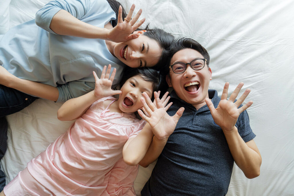 family laying down holding their hands up in the air smiling