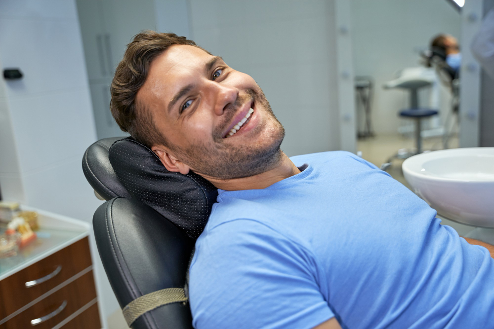 man in blue shirt laying in dental chair smiling