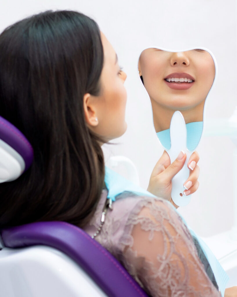woman looking in tooth-shaped mirror looking at her teeth